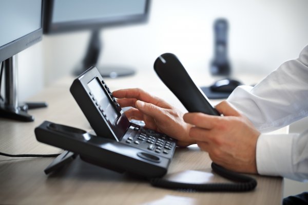 1-voip service review voip services man dialing number on voip phone in office